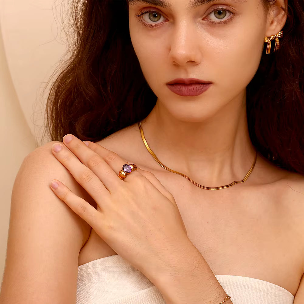 Anillo solitario de piedra morada en acero dorado