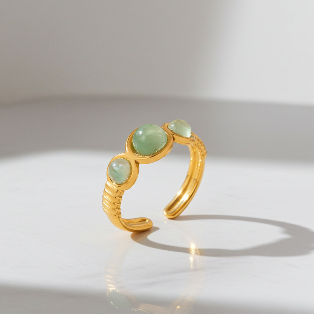 Anillo abierto de piedras verdes en acero dorado