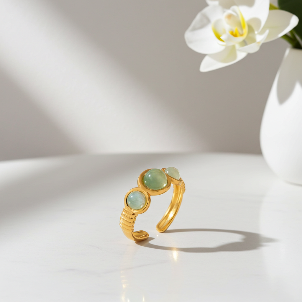 Anillo abierto de piedras verdes en acero dorado