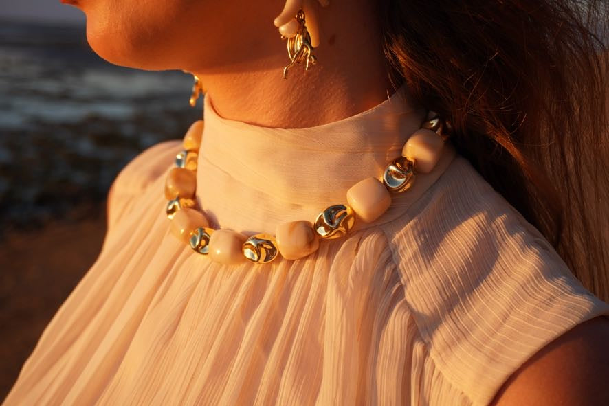 Detalle de joyas BRIORA doradas durante una sesión editorial al atardecer